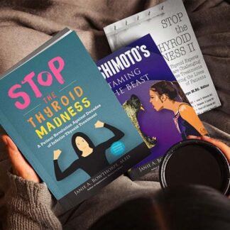 Three books in girl's lap while she's holding a cup of coffee