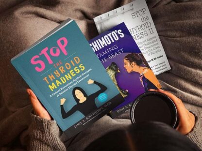 Three books in girl's lap while she's holding a cup of coffee